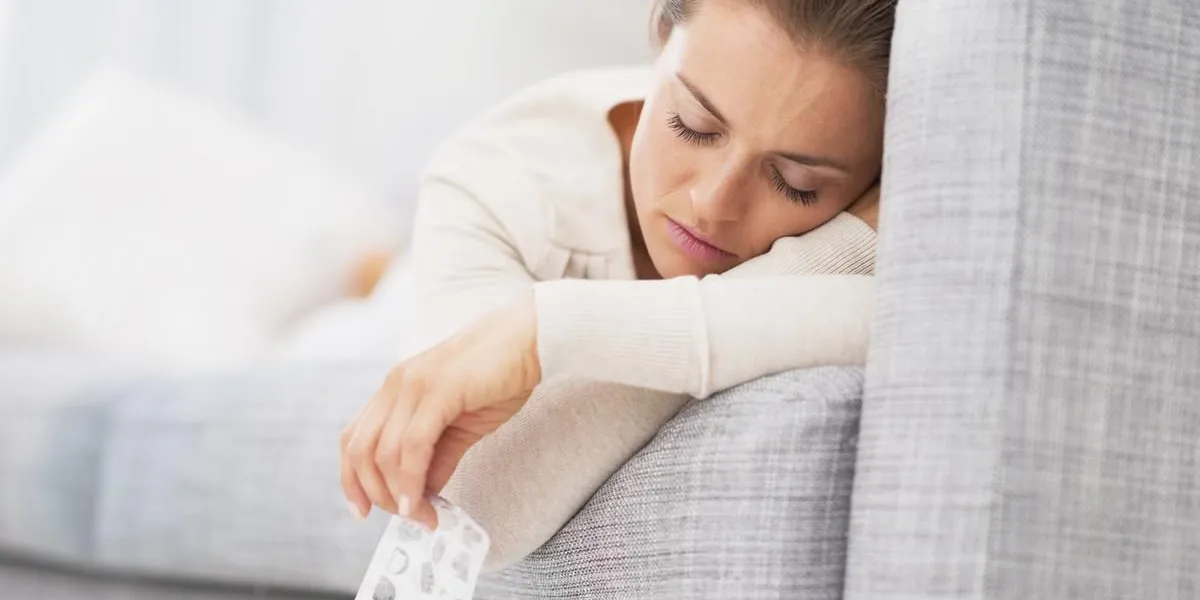 gros plan sur les pilules pack dans la main de la jeune femme malade allongé sur le canapé gros plan sur les pilules pack dans la main de la jeune femme malade allongé sur le canapé