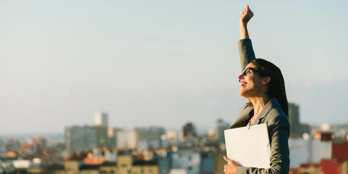 femme d'affaires jeune levant bras célébrant les affaires ou l'accomplissement du travail vers le fond de la ville professionnelle femme heureuse marchant dehors