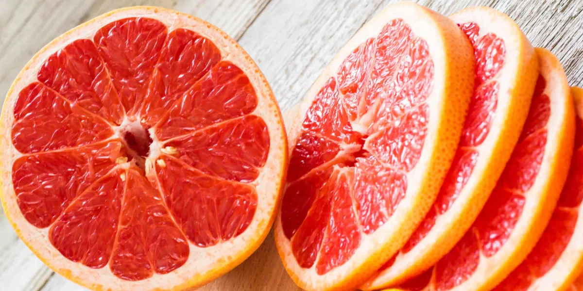 sliced pieces of grapefruit with a knife on white wooden background sliced pieces of grapefruit with a knife on white wooden background
