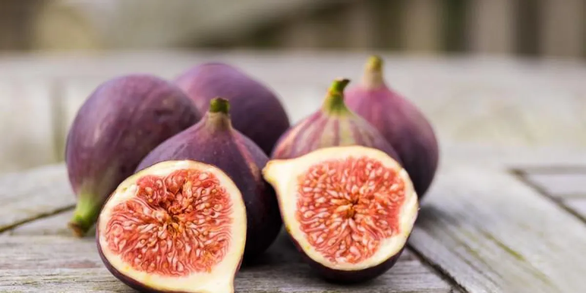 figues entières et une figue coupée en deux sur le dessus d'une table de jardin en teck se concentre sur la figue en tranches figues entières et une figue coupée en deux sur le dessus d'une table de jardin en teck se concentre sur la figue en tranches