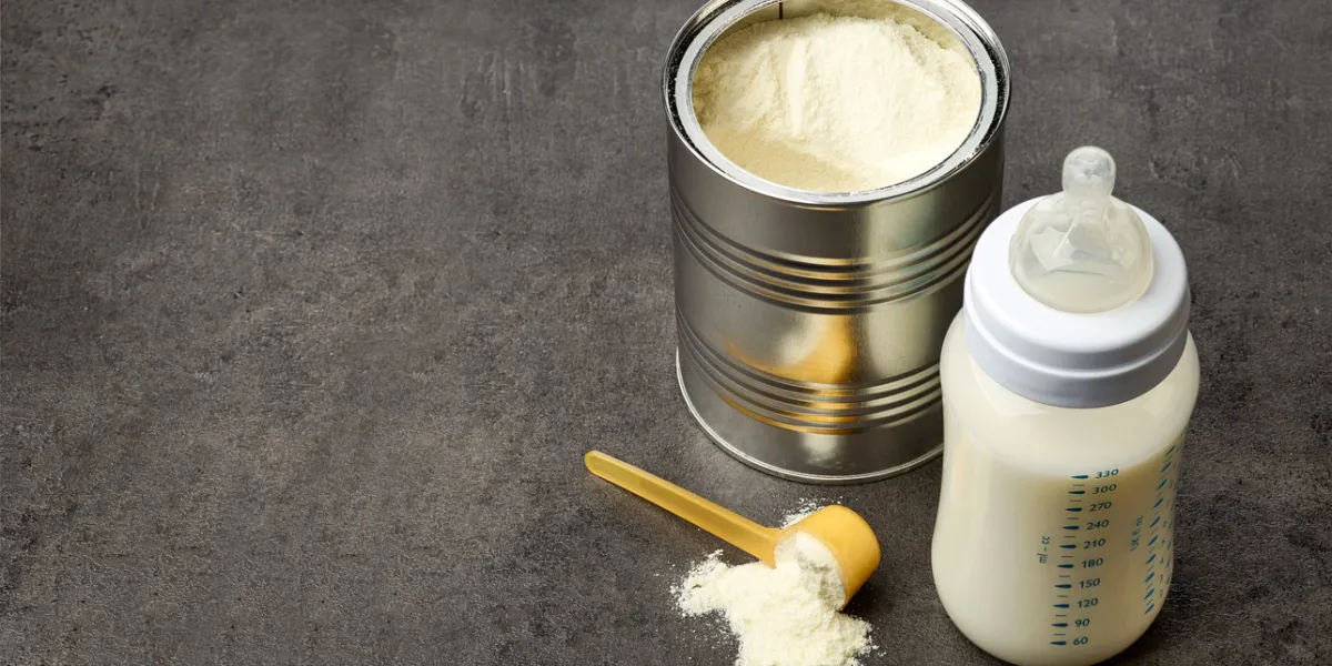 baby bottle and milk powder on dark grey table