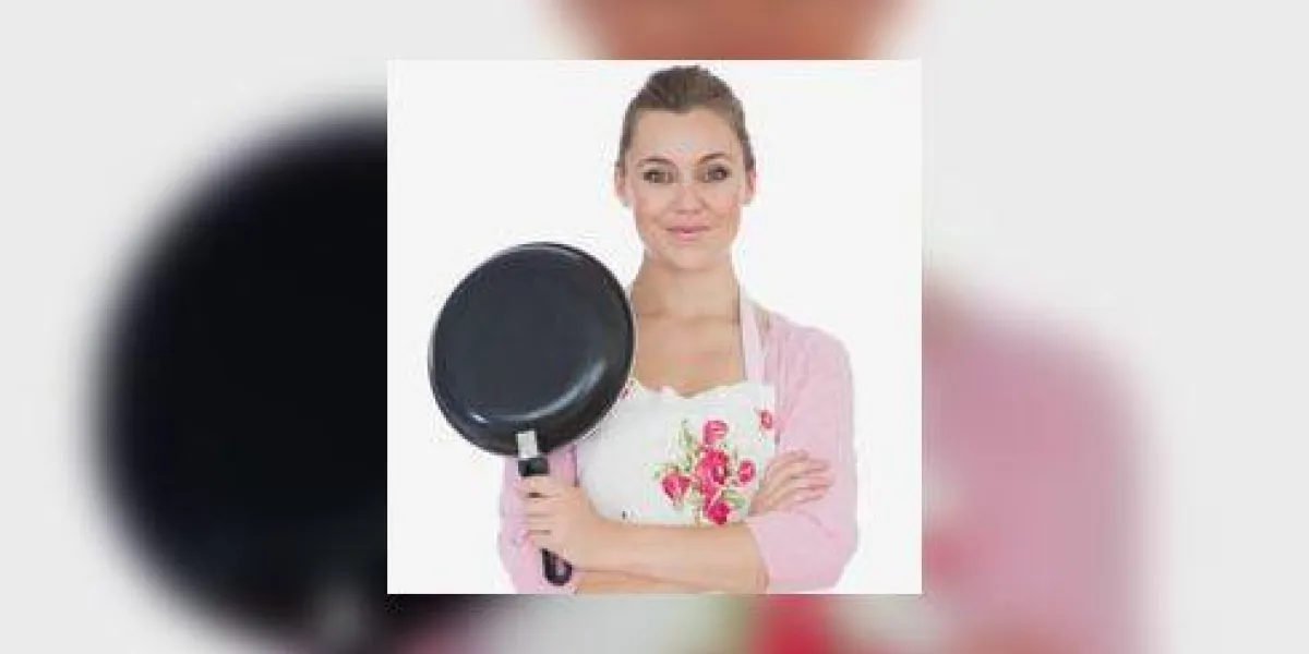 jeune femme aux bras croisés tenant la poêle à frire jeune femme aux bras croisés tenant la poêle à frire