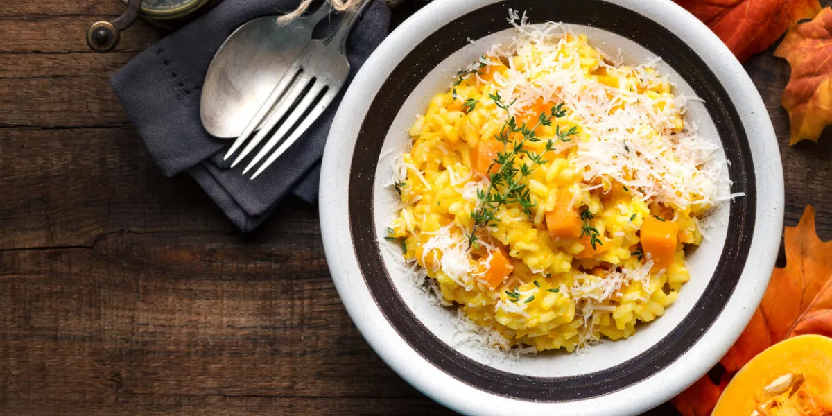 pumpkin risotto with thyme and parmesan cheese against dark wooden background overhead view