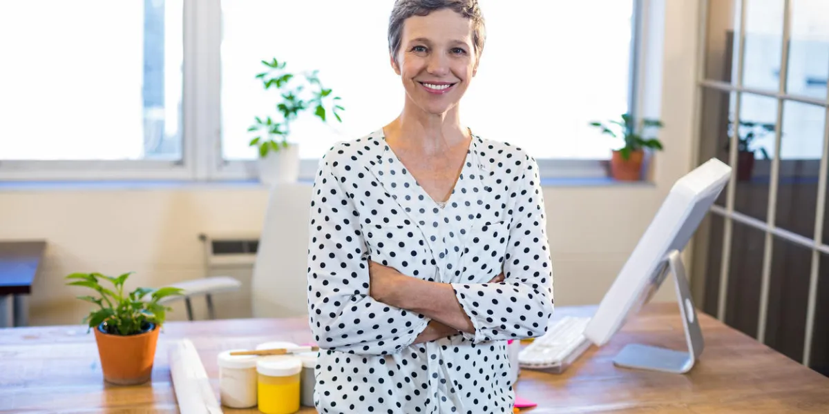 femme souriante debout bras croisés dans le bureau