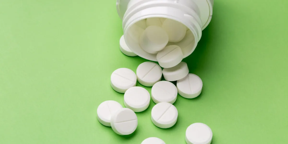 heap of round white tablets and plastic pills bottle