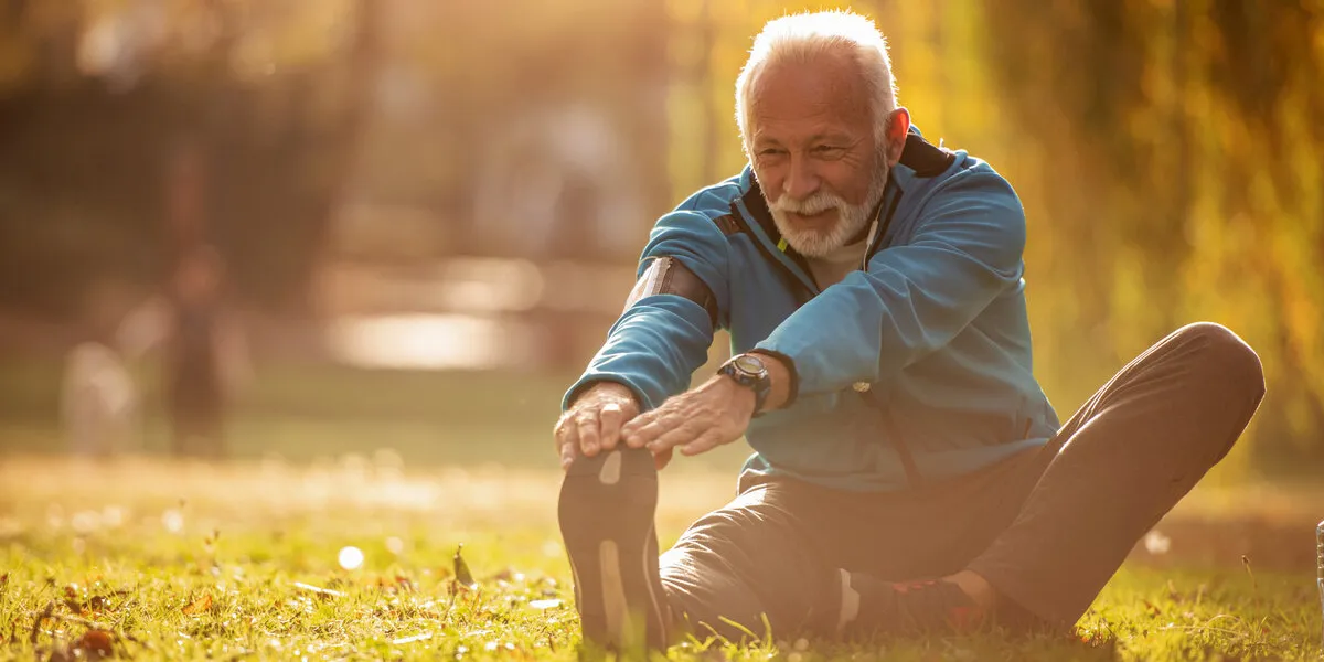 portrait of happy senior man stretching legs in the park portrait of happy senior man stretching legs in the park