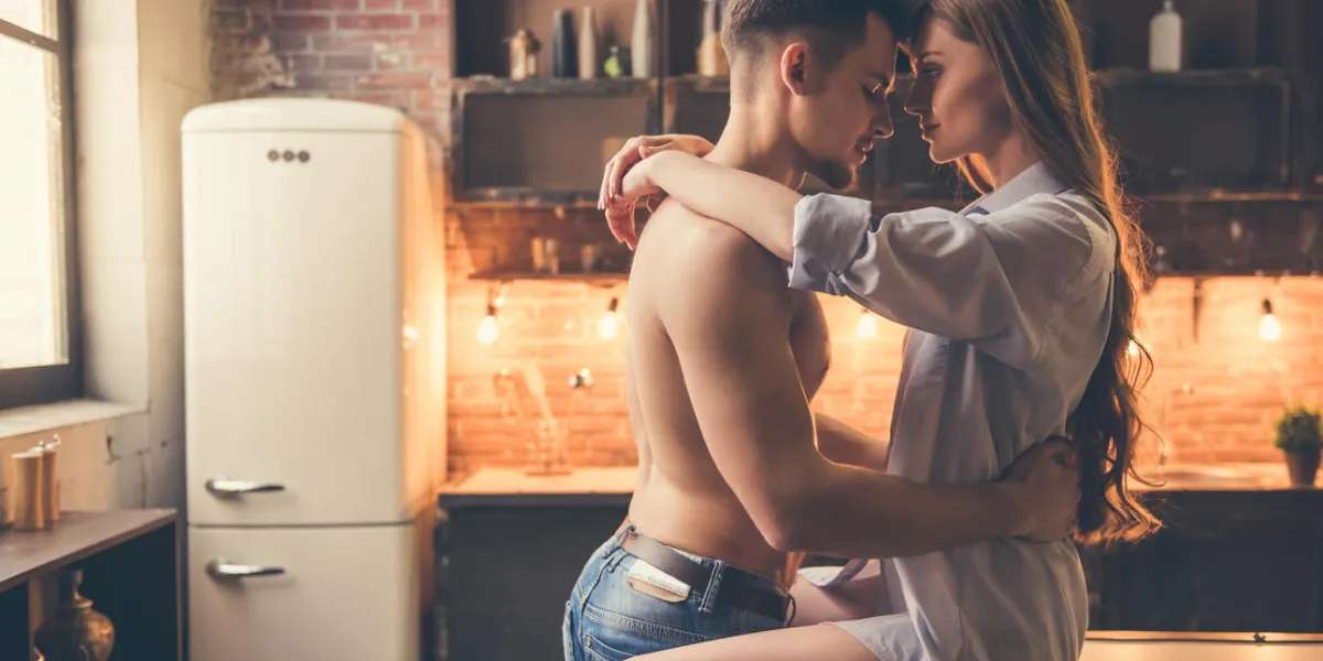 beautiful romantic couple are hugging and smiling while spending time together in kitchen at home