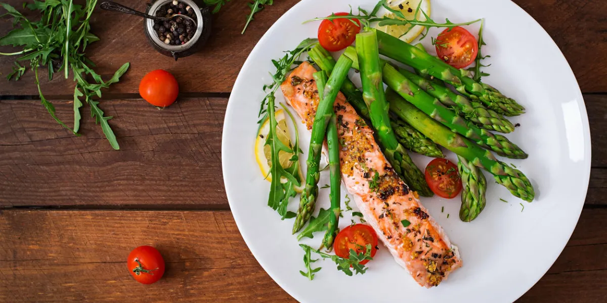 baked salmon garnished with asparagus and tomatoes with herbs top view