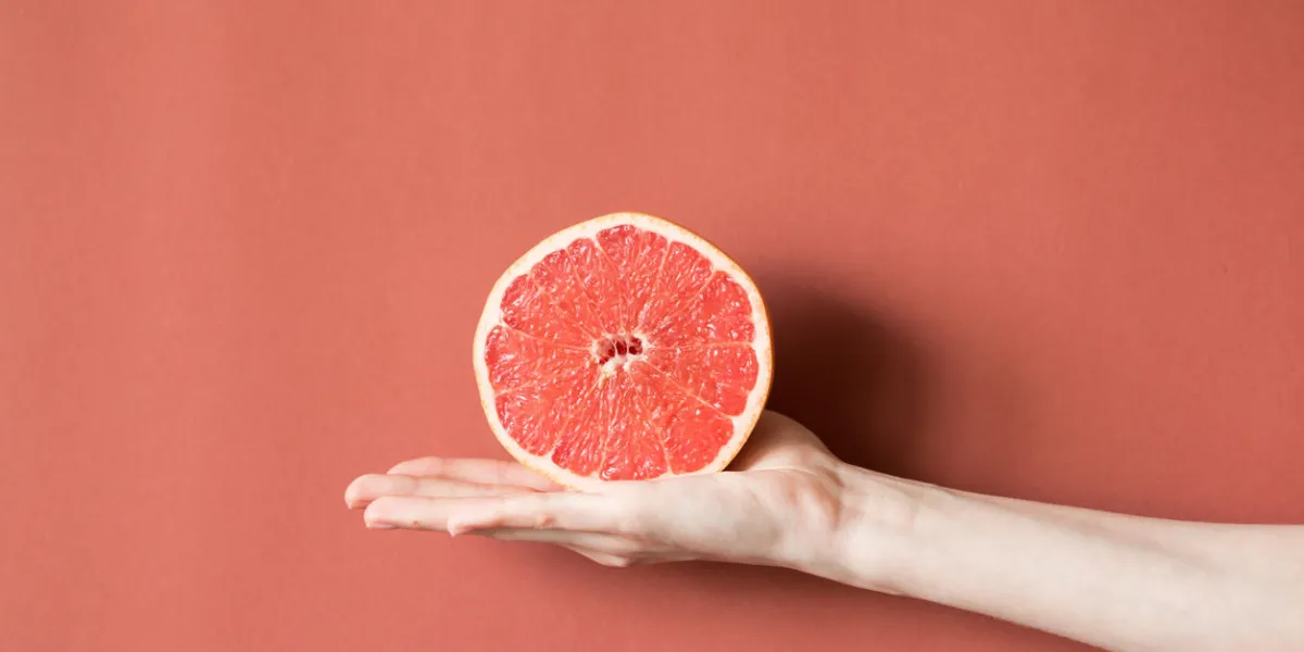 hands of a young woman holding a red grapefruit healthy food concept hands of a young woman holding a red grapefruit healthy food concept