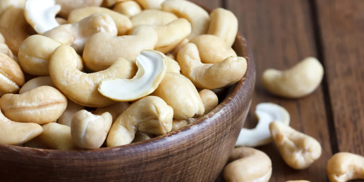 wooden bowl of cashew nuts from above on dark wood wooden bowl of cashew nuts from above on dark wood