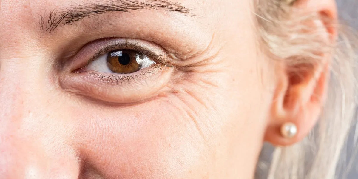 macro of the eye of a smiling woman showing signs of age such as crow's feet and wrinkles