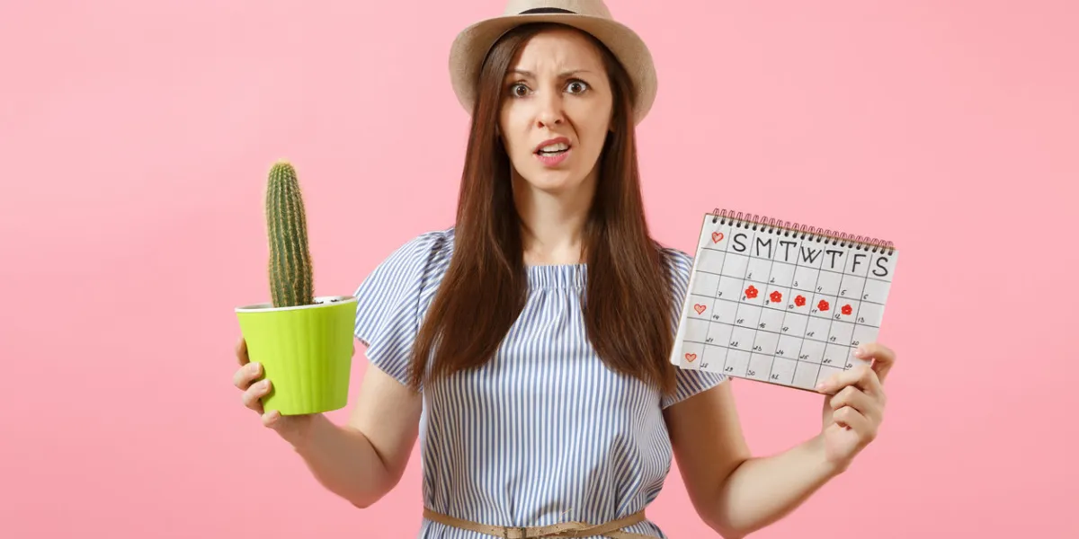 sad sickness woman in blue dress holding green cactus, periods calendar for checking menstruation days isolated on pink background medical, healthcare, gynecological, tummy pain concept copy space sad sickness woman in blue dress holding green cactus, periods calendar for checking menstruation days isolated on pink background medical, healthcare, gynecological, tummy pain concept copy space