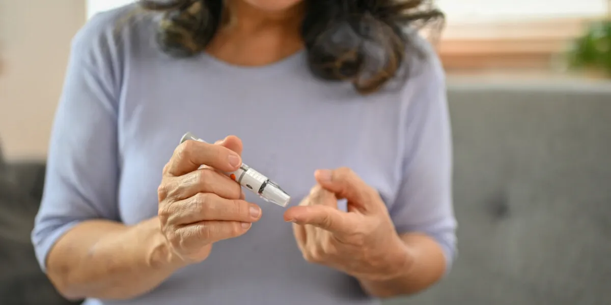 close-up image of a sick 60-year-old asian woman using a lancet on her finger to measure her blood sugar level at home diabetes, glycemic and health care concept close-up image of a sick 60-year-old asian woman using a lancet on her finger to measure her blood sugar level at home diabetes, glycemic and health care concept