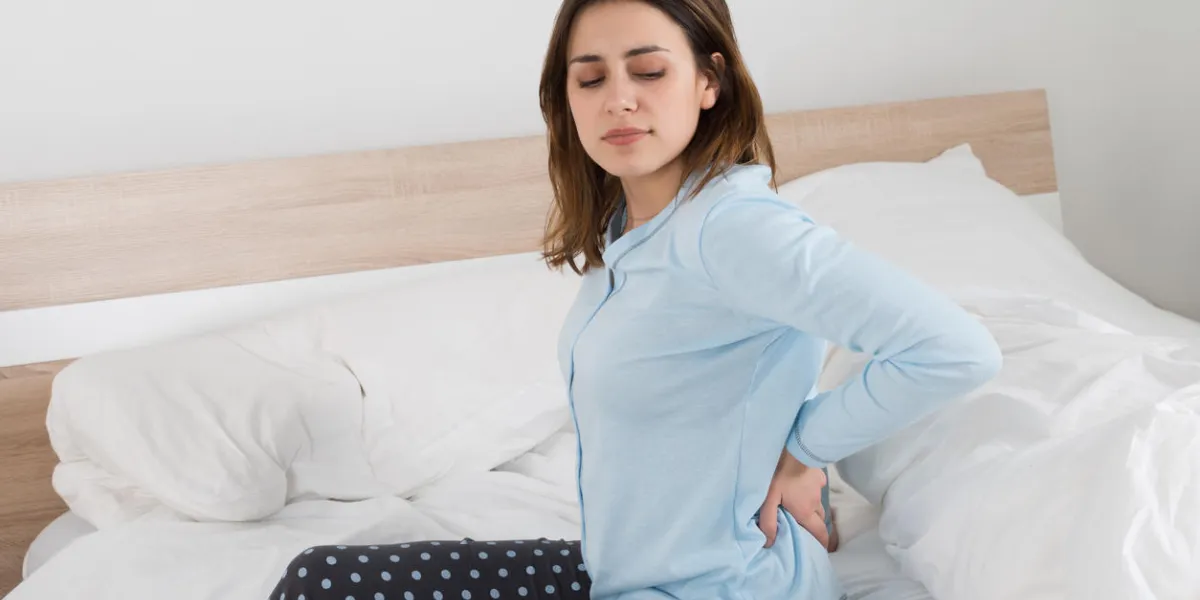 femme souffrant de maux de dos assis sur le lit