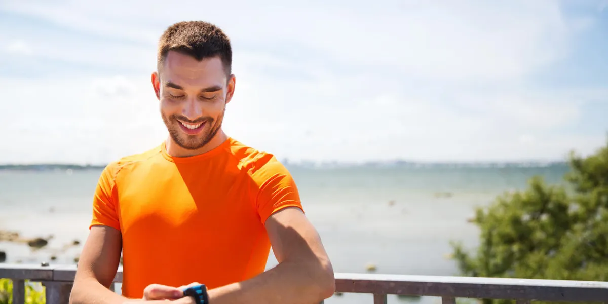 fitness, sport, gens, technologie et concept de mode de vie sain - souriant jeune homme avec montre-bracelet intelligente en été balnéaire