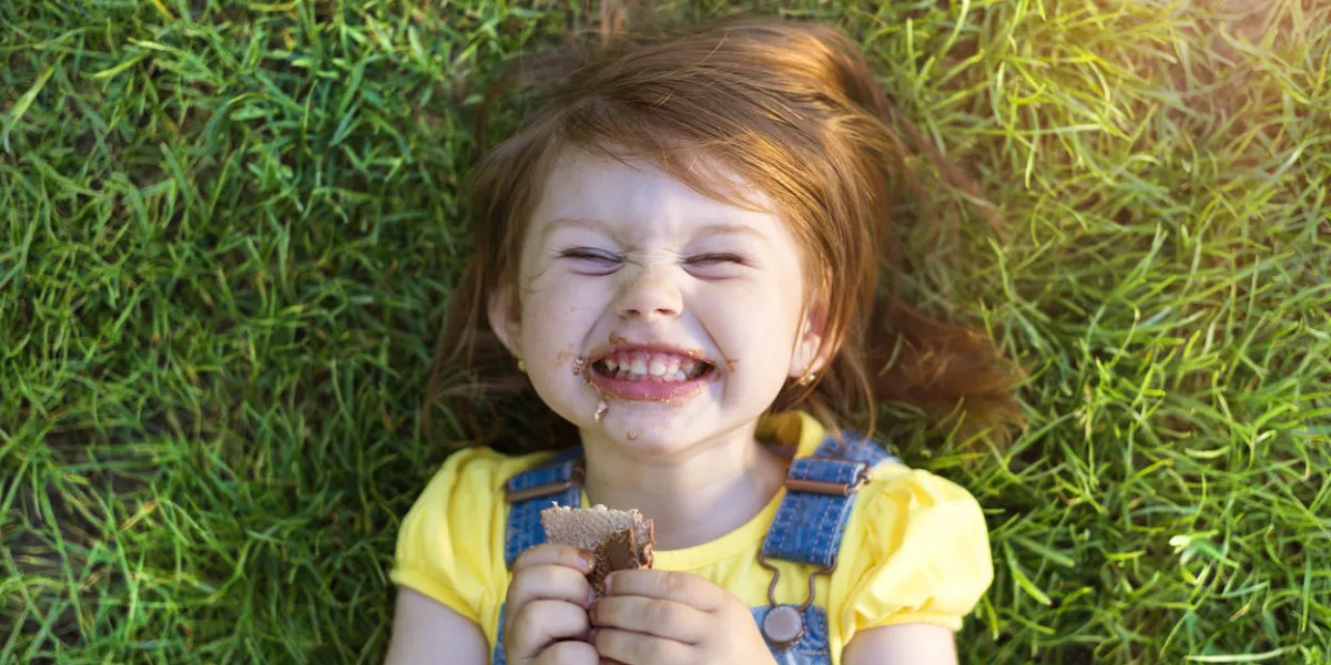 cute little girl with chocolate face lying on a grass