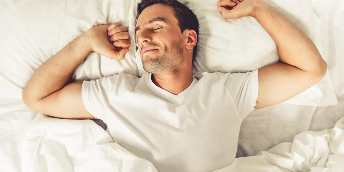 vue de dessus du bel homme souriant tout en dormant dans son lit à la maison vue de dessus du bel homme souriant tout en dormant dans son lit à la maison
