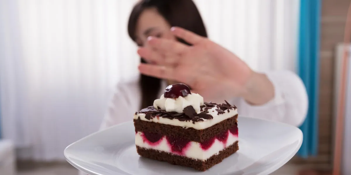woman refusing slice of delicious cake offered by a person