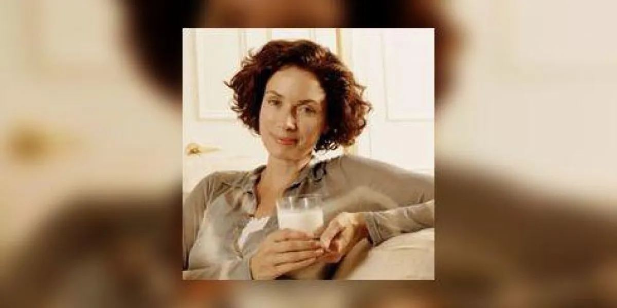 femme tenant un verre de lait et souriant à la caméra femme tenant un verre de lait et souriant à la caméra