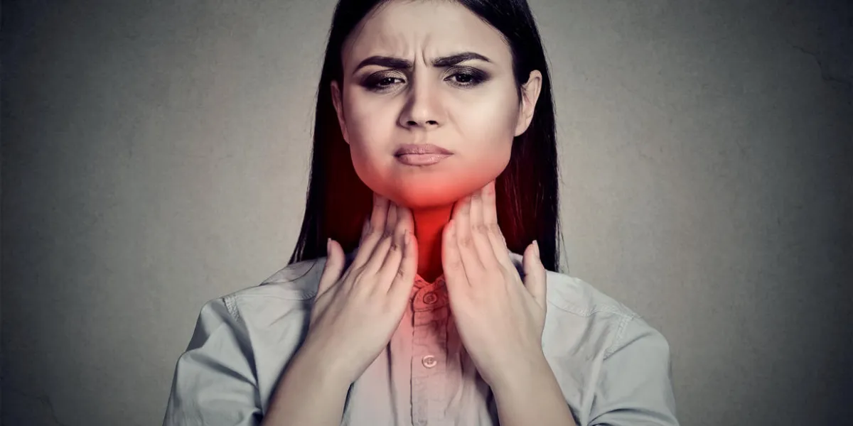 woman with sore throat touching her neck colored in red isolated on gray wall background woman with sore throat touching her neck colored in red isolated on gray wall background