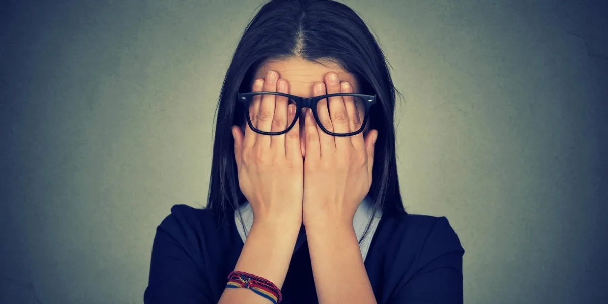 closeup portrait jeune femme dans des verres couvrant les yeux du visage en utilisant ses deux mains isolées sur fond de mur gris