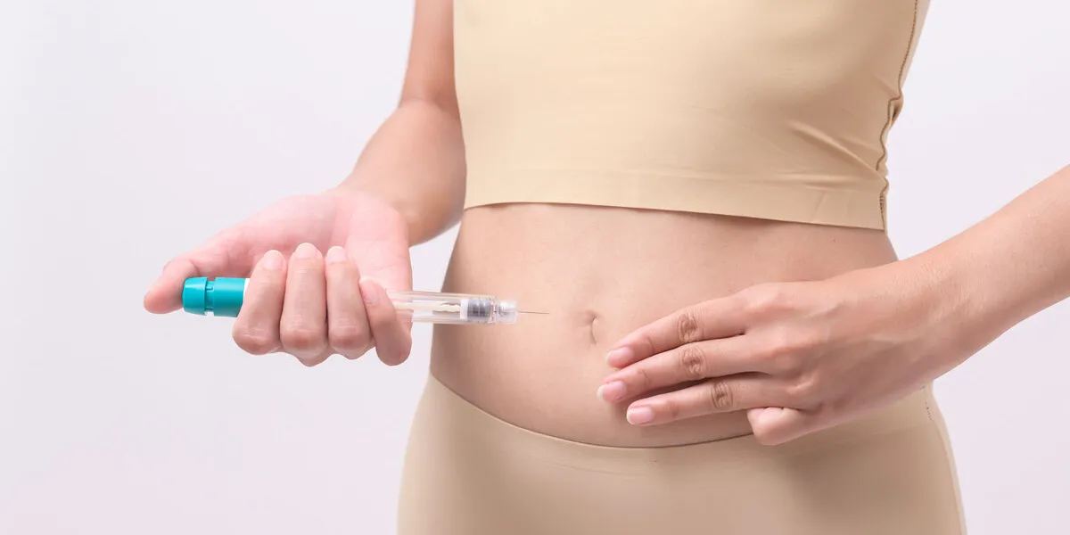 close up woman using ivf treatment injection on belly to prepare reproductive fertility , ovulation stimulation