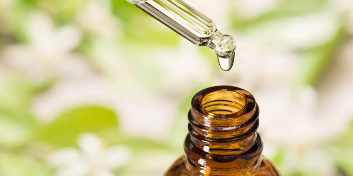 essential oil in the glass dropper, with orange flower background