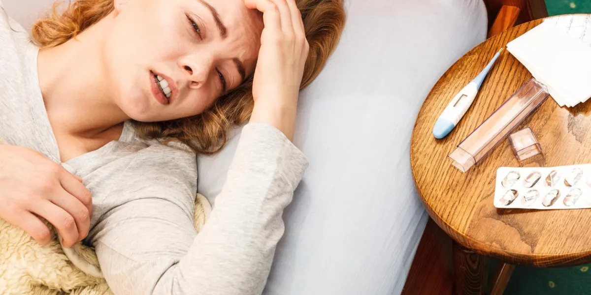 sick woman suffering from headache pain ill girl laying in bed caught cold thermometer and pills on table sick woman suffering from headache pain ill girl laying in bed caught cold thermometer and pills on table