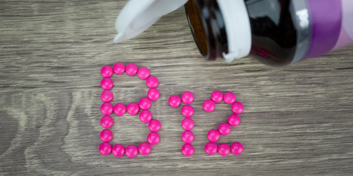 pink pills forming shape to b12 alphabet on wood background