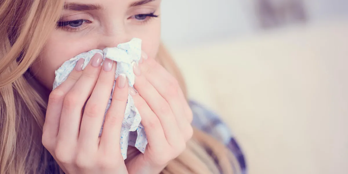 young european woman siitng on bed with running nose and tissues concept of illness and resting flu epidemic began