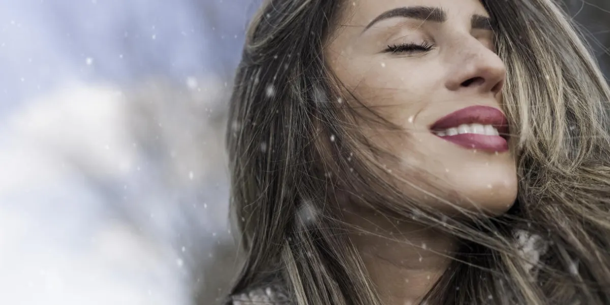 fille appréciant la première neige avec les yeux fermés par une journée ensoleillée