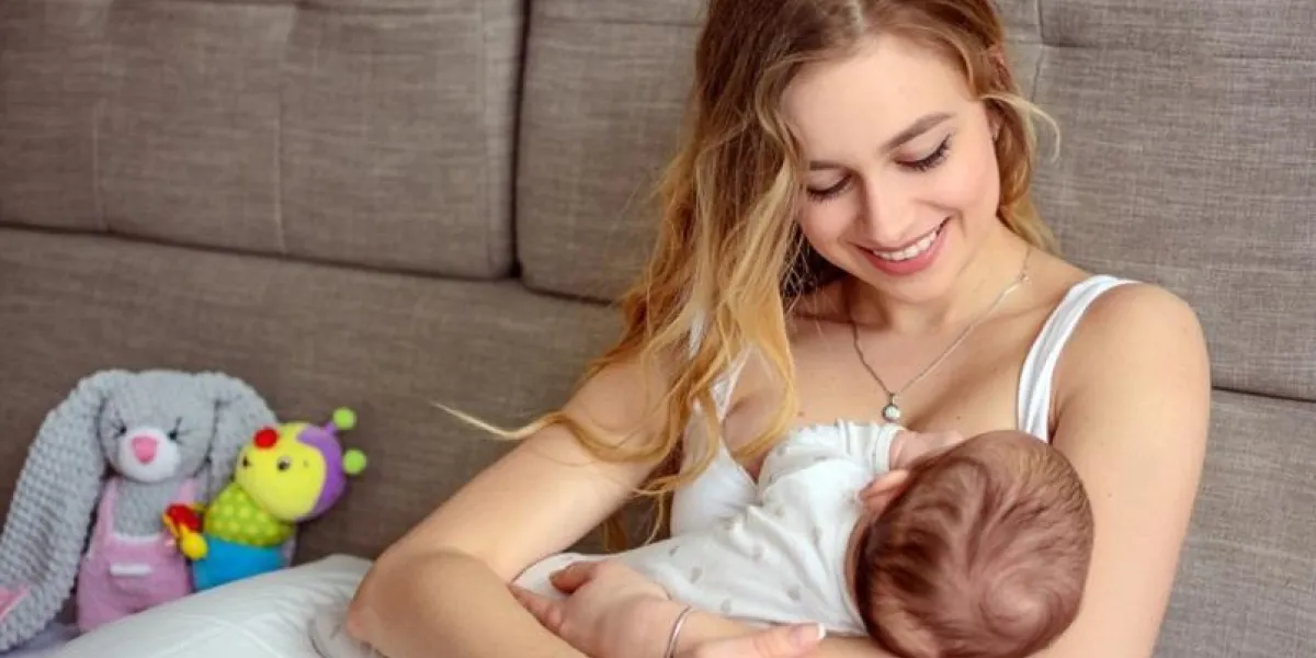 breastfeeding baby pretty mother holding her newborn child mom smile and nursing infant beautiful woman and new born love at home blond mother breast feeding baby