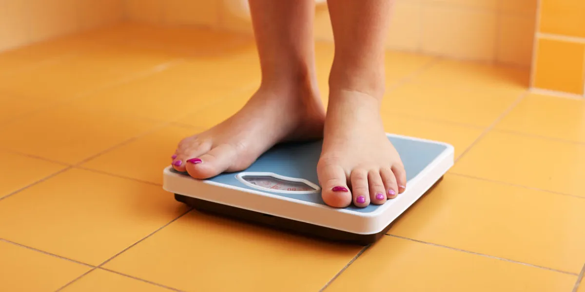 a pair of female feet standing on a bathroom scale a pair of female feet standing on a bathroom scale