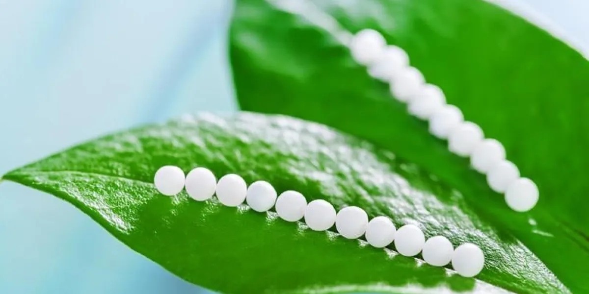 macro close up of homeopathic pills on green leaves against blue background