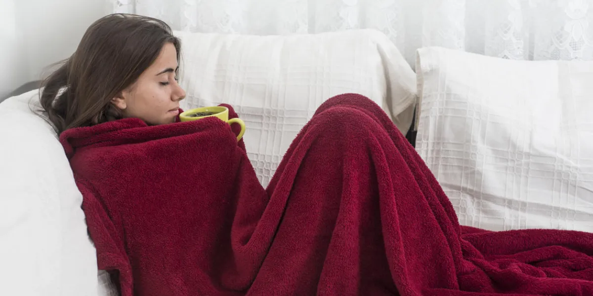 ill young girl with fever drinking cup of warm tea