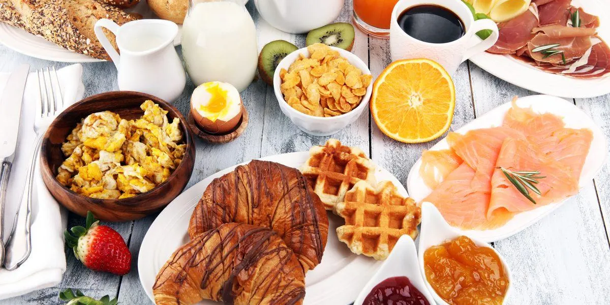breakfast on table with waffles, croissants, coffe and juice