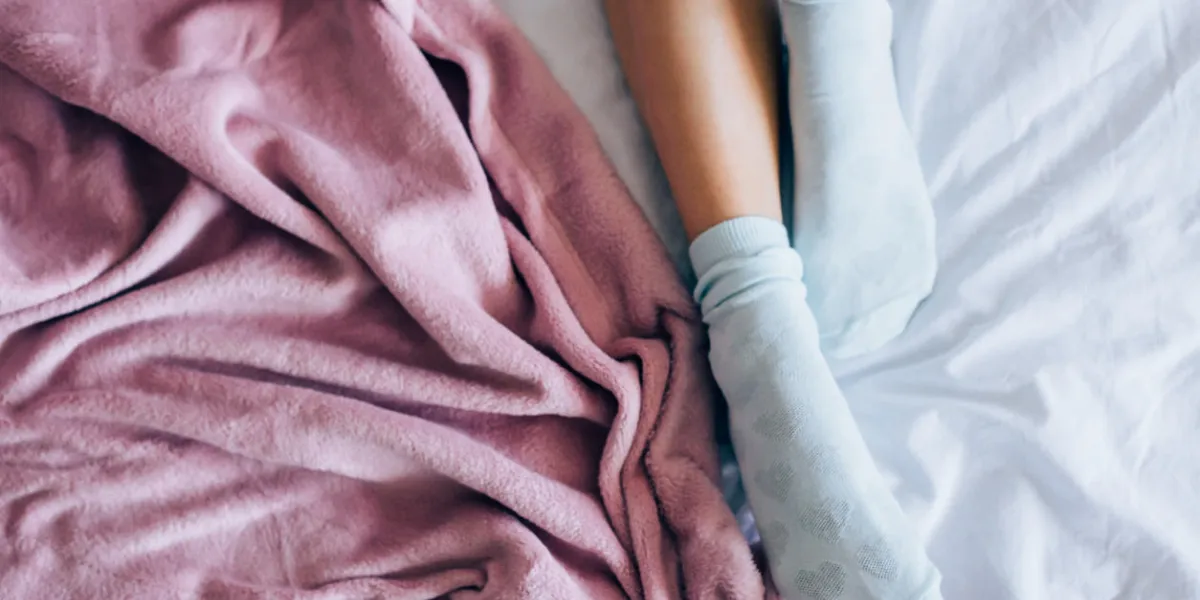 legs of girl in warm socks in bad, winter morning at home
