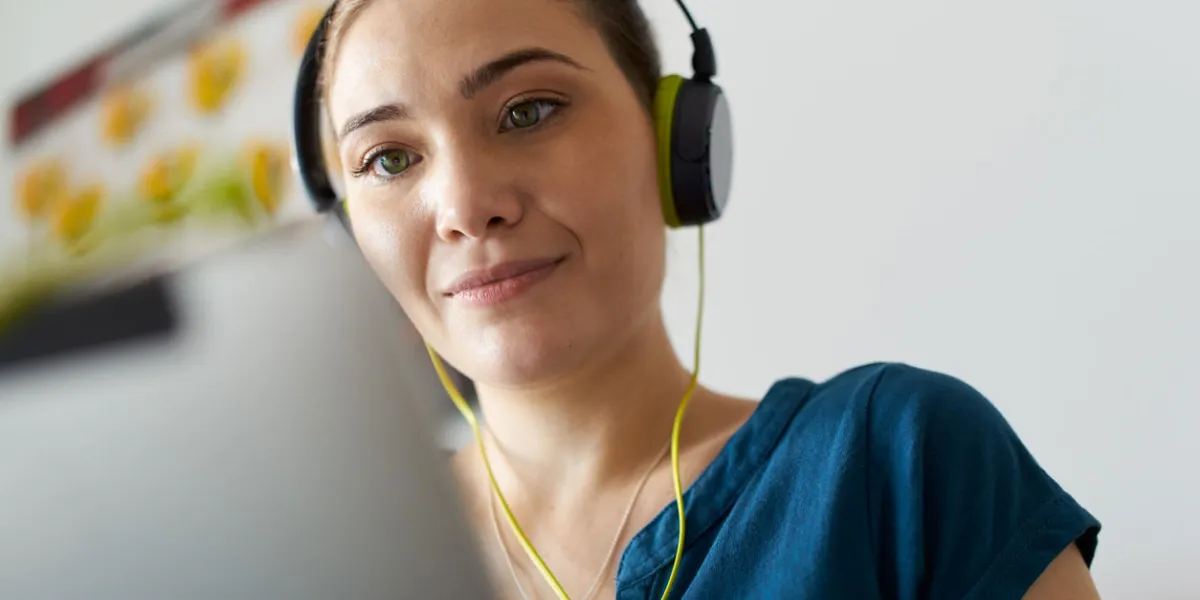 belle femme se détend sur le canapé et regarde podcast sur tablet pc, écoutant avec de grands écouteurs verts copie espace