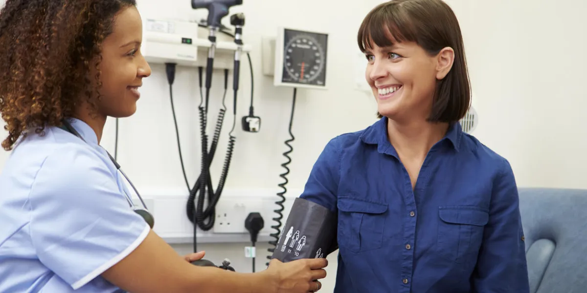infirmière prenant la pression artérielle du patient à l'hôpital en regardant les uns les autres en souriant infirmière prenant la pression artérielle du patient à l'hôpital en regardant les uns les autres en souriant