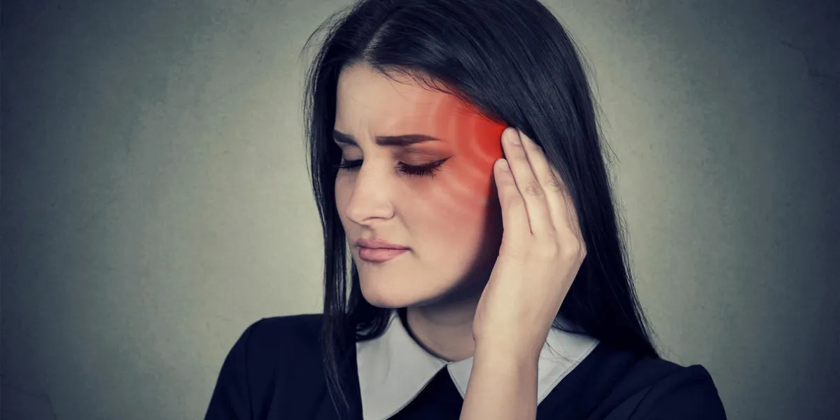 tinnitus closeup up side profile sick female having ear pain touching her painful head temple colored in red isolated on gray wall background tinnitus closeup up side profile sick female having ear pain touching her painful head temple colored in red isolated on gray wall background
