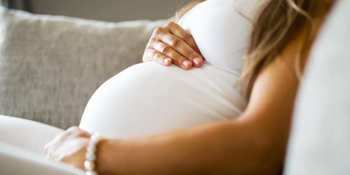 close-up of pregnant woman relaxing and sitting on the side on the sofa holding a hands on the tummy close-up of pregnant woman relaxing and sitting on the side on the sofa holding a hands on the tummy