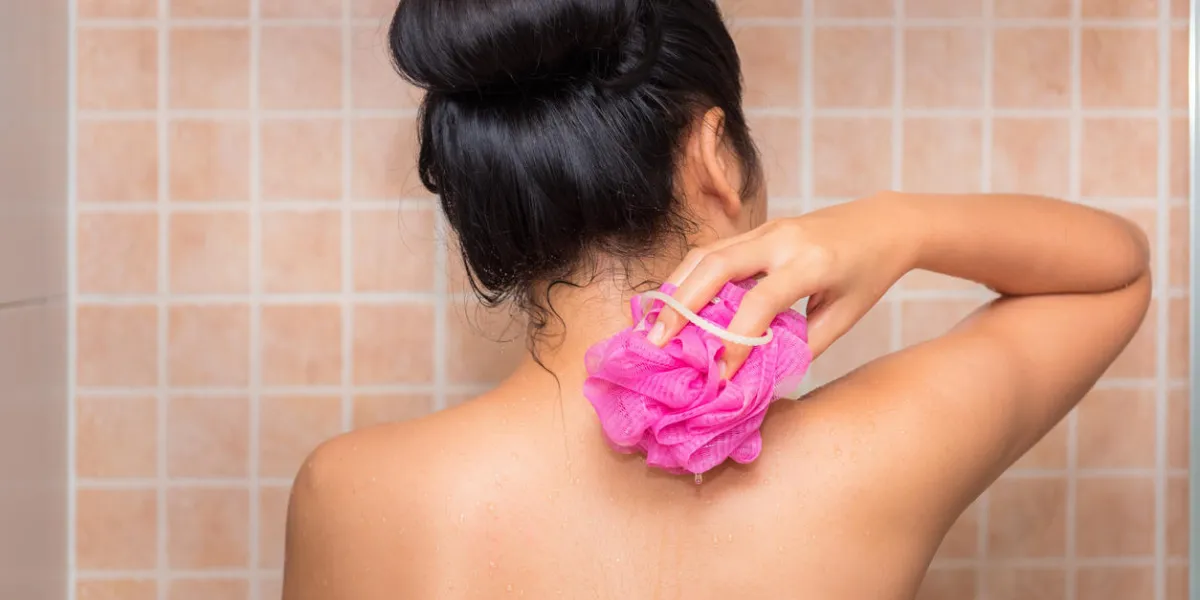 portrait of beautiful woman taking shower with bath sponge and soap