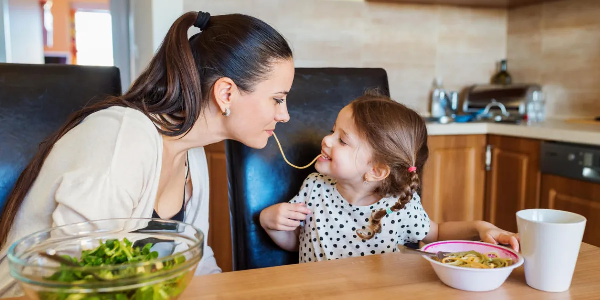 jeune maman avec sa petite fille mignonne dans la cuisine, manger des spaghettis ensemble