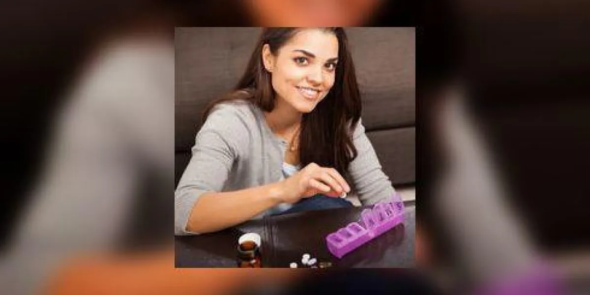 belle jeune femme trier certaines de ses pilules sur un organisateur de pilules à la maison