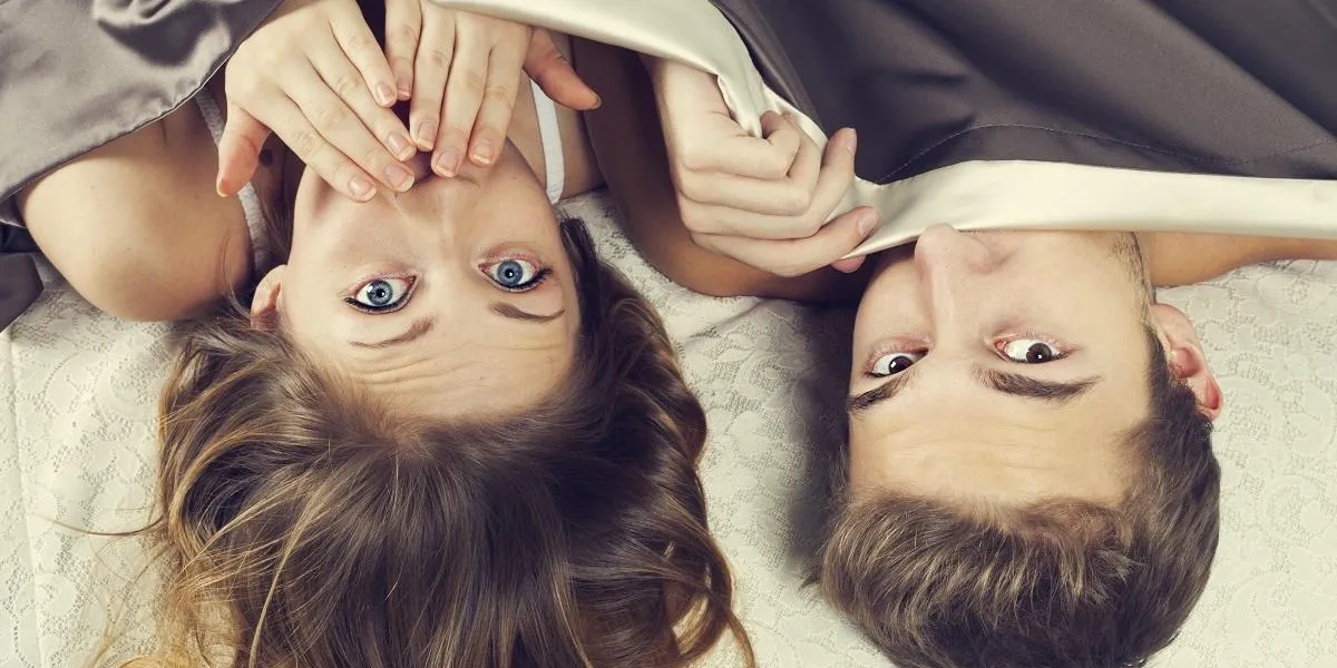 frightened young couple under the sheets - shock concept