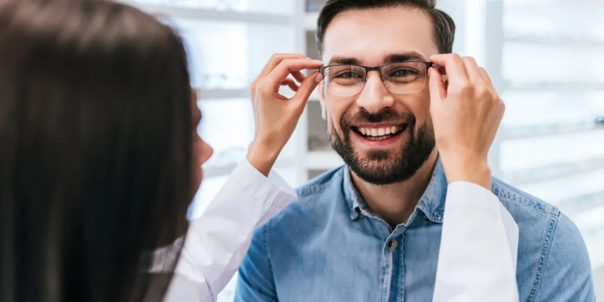 young female doctor ophthalmologist is helping handsome man to choose the most appropriate eyeglasses doctor and patient in modern ophthalmology clinic