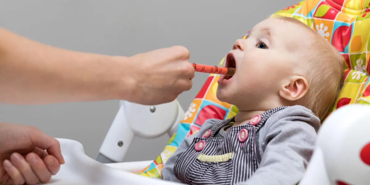 mother giving cough syrup with syringe to her sick baby