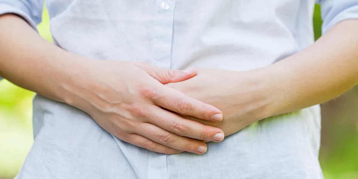 close up picture of a pregnant woman holding her belly in the first trimester, outdoor