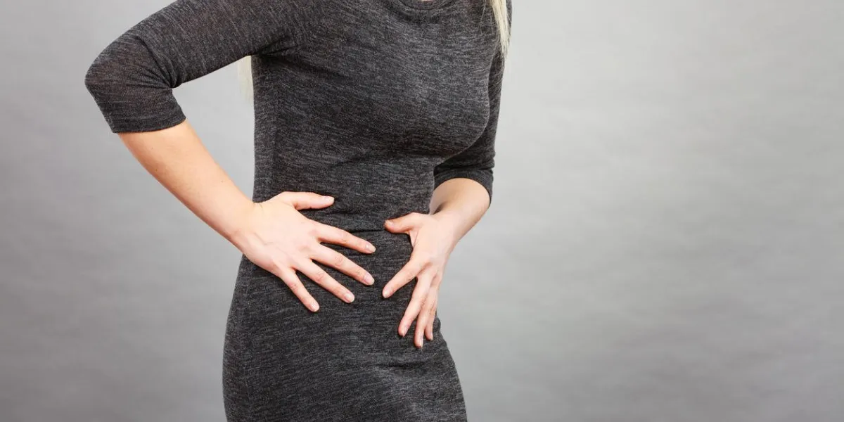 woman having strong stomach ache syndroms of indigestion pregnancy female suffer on belly pain, holds hands on abdomen, part of body on grey
