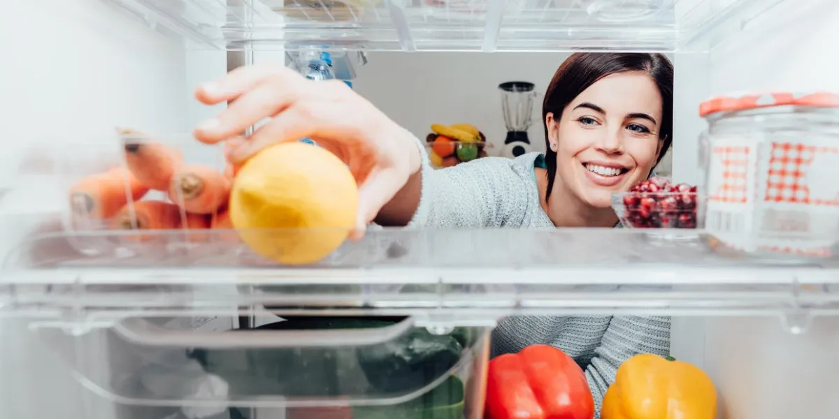 smiling woman taking a fresh lemon out of the fridge, healthy food concept smiling woman taking a fresh lemon out of the fridge, healthy food concept